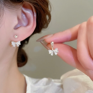 Macro shot of silver bow earrings with sparkling cubic zirconia worn by a model