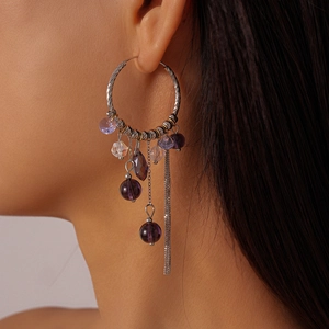 Detail of silver hoop earrings with purple crystal beads and elegant metal tassels on model
