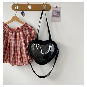 Detail of a black heart-shaped ita bag with a clear PVC window and adjustable shoulder strap