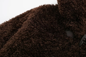 Detailed view of dark brown faux fur texture and black horn buckle on winter coat