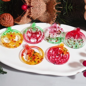 Dettaglio di ciondoli natalizi in resina con glitter e fiocchi su un piatto di ceramica