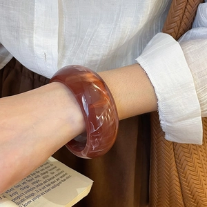 Close-up of marble textured resin bangle on wrist with vintage aesthetic background