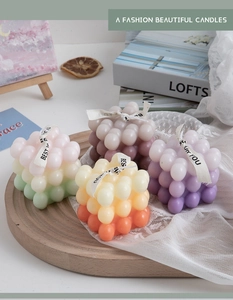 Macro detail of cube bubble candles in gradient colors with decorative ribbons and tray