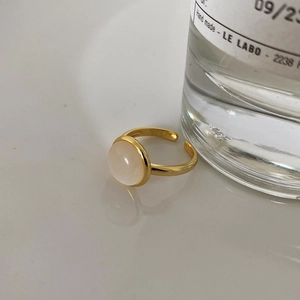 Close-up of a minimalist gold open ring with a round white cabochon gemstone