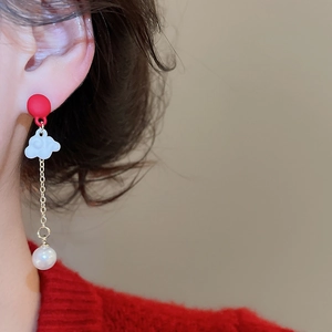 Macro view of Chinese lion dance earrings with red studs, white clouds and pearls