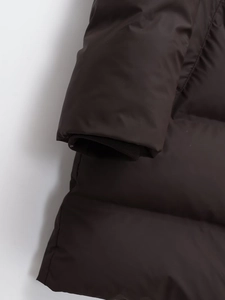 Detailed close-up of dark brown down coat featuring windproof ribbed storm cuffs design