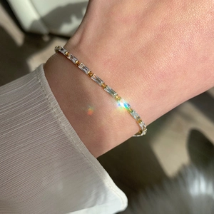 Detailed close-up of a gold bracelet with rectangular AAA zircons on a woman wrist