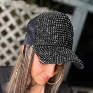 Close-up of black rhinestone baseball cap worn by model showing textured crystal details