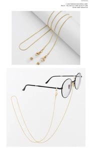 Detail of a golden snake chain eyewear strap with metal clasps and silicone loops