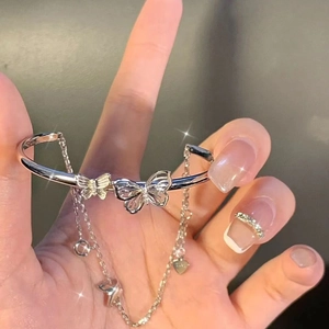Detail of silver bracelet featuring butterfly charms and heart dangle chain on wrist