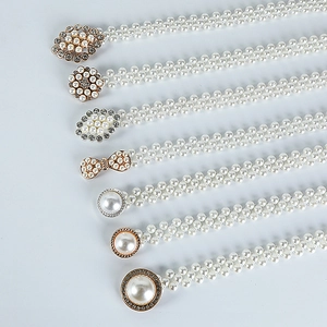 Detail of assorted pearl waist belts featuring floral and bow-shaped rhinestone buckles