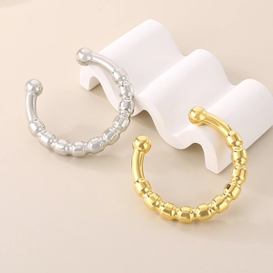 Detail showing high-polish gold and silver C-shape hollow bangles on a wavy display stand