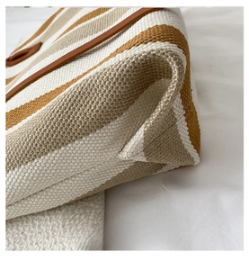 Close-up of the reinforced brown leather edges and striped canvas texture of the tote bag