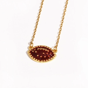 Detail of a golden American football pendant featuring vibrant red enamel and textured gold stitching