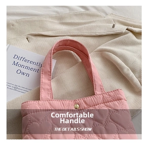 Detail of pink quilted tote bag with heart stitching and golden snap fastener closure