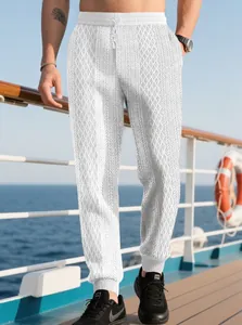 Dettaglio dei pantaloni in maglia jacquard bianca con motivo a rombi e coulisse in vita
