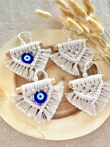 Detail view of handmade beige macrame wall hangings with blue evil eye beads and wood rods