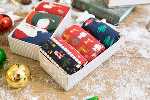 Festive holiday gift box with knitted Christmas socks featuring reindeer and Santa patterns