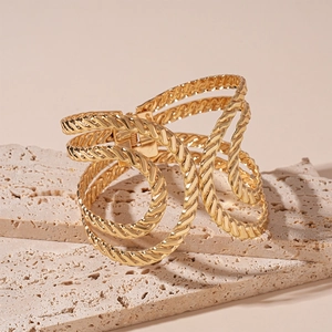 Detail of the golden multi-layer spiral textured cuff bracelet on stone background
