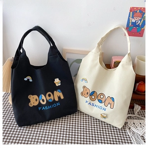 Detailansicht der schwarzen und beigen Canvas-Tragetaschen mit BOOM FASHION Bär-Stickerei