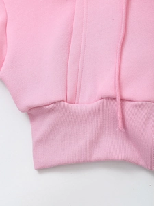 Detail of pink hoodie featuring ribbed cuffs and matching drawstring on soft knit fabric