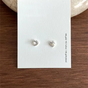 Macro shot of minimalist 925 sterling silver heart earrings with white pearl inlay detail