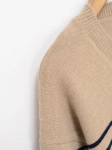 Detailed close-up of ribbed crewneck and textured shoulder seams on khaki striped sweater