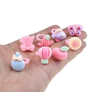 Close-up of assorted pink plastic cartoon rings for girls in palm of hand