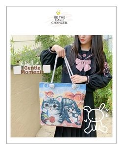 Detail of woven jacquard tote bag featuring a cat and goldfish pattern with cotton ropes