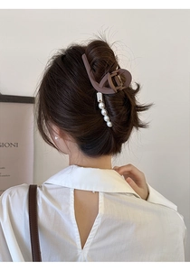 Gros plan d'une pince à cheveux mate marron ornée de cinq perles blanches