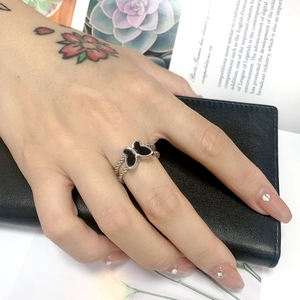 Detail of a silver butterfly ring with black inlay and twisted rope band worn on a hand