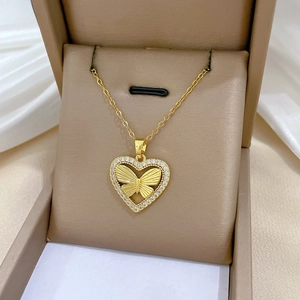 Close-up of gold heart-shaped pendant with butterfly detail and sparkling zircons