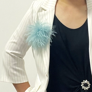 Close-up of fluffy light blue ostrich feather brooch on a white pinstripe suit
