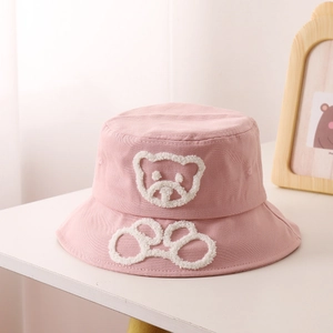 Détail d'un chapeau bob rose pour enfants avec ours en peluche 3D et broderie bouclée