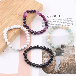 Detailed view of four types of 8mm natural stone beaded bracelets on a magazine background