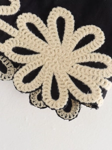 Gros plan de la broderie de fleurs au crochet crème sur le détail du tissu tissé noir