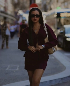 Détail de l'ensemble cardigan et minijupe en maille bordeaux avec un sac bandoulière