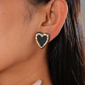 Vintage heart-shaped stud earring in gold and black, worn by a model in a side profile view
