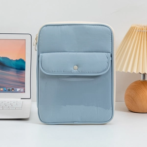 Close-up of a light blue quilted laptop sleeve with a snap button pocket and zipper