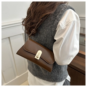 Detail of vintage brown shoulder bag showing golden oval lock and knot strap detail