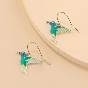 Detailed close-up of hummingbird drop earrings with blue and green enamel and gold finish