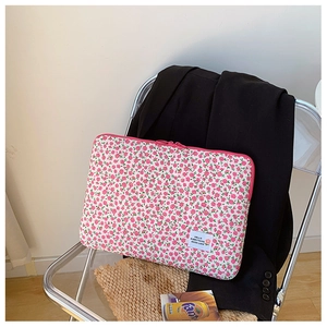 Detailed view of pink floral laptop sleeve with HELLO EVERYTHING GOOD LUCK cloth label