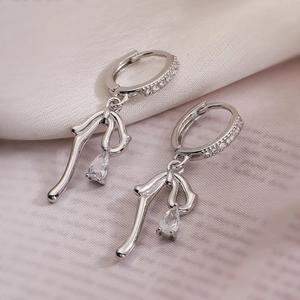 Silver bow knot earrings with zircon drop pendants on soft fabric background