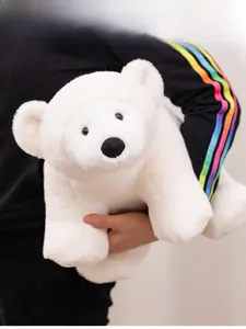 Close-up of a soft white plush polar bear toy held by hand for scale comparison