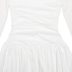 Detail of white dress featuring crossover waist folds and elegant pleated fabric texture