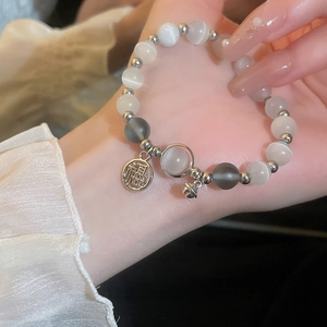 Detailed shot of cat eye beads bracelet with Fu character charm and small silver bell