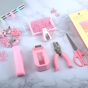 Set cancelleria rosa per ufficio e scuola con cucitrice su sfondo di marmo