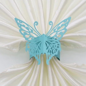 Detail of sky blue butterfly paper napkin ring on a white satin napkin for weddings