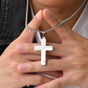 Close-up of a silver textured cross necklace with a small crystal on a male model