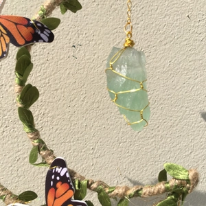Detail of green natural crystal stone hand-wrapped in gold wire with leaf accents